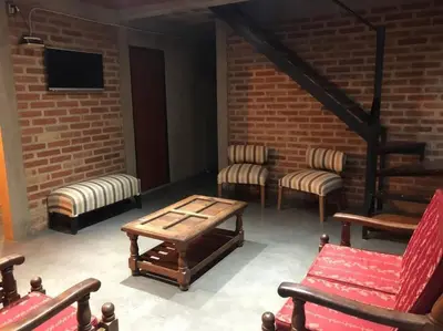 a room with chairs and a table and a brick wall at Cabaña RUSTICA exclusiva para 6 personas toda equipada in Carpintería