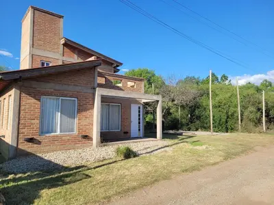 a brick house with a white door in a yard at Cabaña RUSTICA exclusiva para 6 personas toda equipada in Carpintería