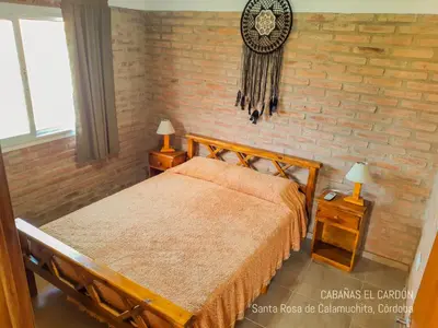a bedroom with a bed and a brick wall at Cabañas El Cardón in Santa Rosa de Calamuchita