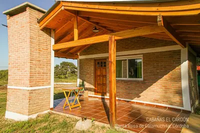 a wooden pergola on a house with a table at Cabañas El Cardón in Santa Rosa de Calamuchita