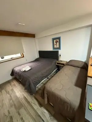 a bedroom with two beds and a table and a window at Departamento amoblado con amenities 106 INVERHOME INMOBILIARIA in Cordoba