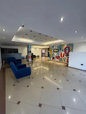 a lobby with a blue chair and a white tile floor at Departamento amoblado con amenities 106 INVERHOME INMOBILIARIA in Cordoba
