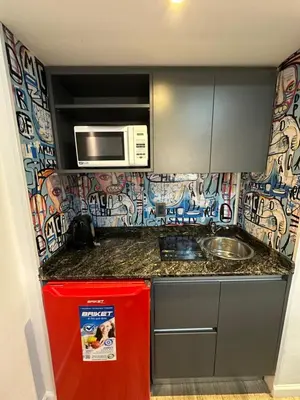 a small kitchen with a microwave and a red refrigerator at Departamento amoblado con amenities 106 INVERHOME INMOBILIARIA in Cordoba