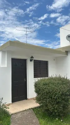 a white house with a black door on it at 760 C Apartamentos in Alta Gracia