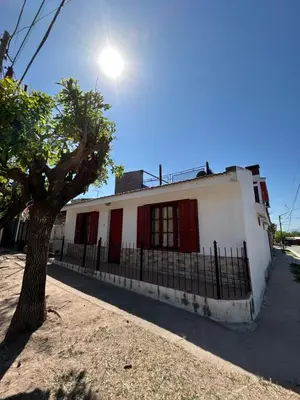 a white building with red doors and a tree at La Colina - Cosquín in Cosquín