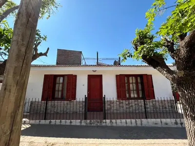 a white house with red doors and a fence at La Colina - Cosquín in Cosquín