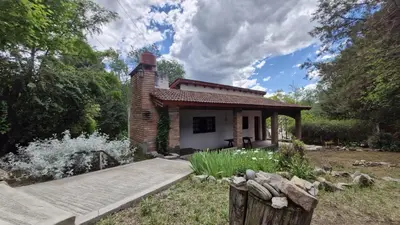 a small brick house in the middle of a garden at Lucía Haus in Villa General Belgrano
