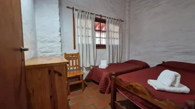 a bedroom with two beds and a window and a table at Lucía Haus in Villa General Belgrano