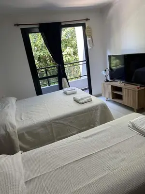 a bedroom with two beds and a tv and a window at Miralejos 17 in Villa Carlos Paz