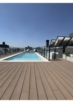 a swimming pool on top of a building with a wooden deck at Departamento Moderno Céntrico in Villa Carlos Paz