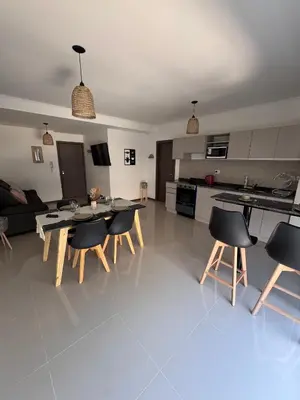 a kitchen and living room with a table and chairs at Departamento Moderno Céntrico in Villa Carlos Paz