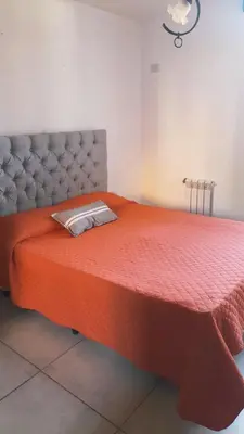 a large orange bed with a red comforter at Dpto Tempo Carlos Paz in Villa Carlos Paz