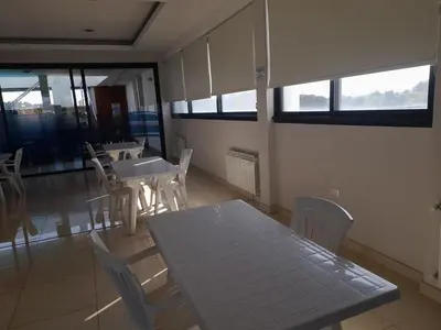 a dining room with a table and chairs and windows at Dpto Tempo Carlos Paz in Villa Carlos Paz