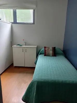 a bedroom with a bed with a green comforter and a window at Casa Los Algarrobos in Cordoba