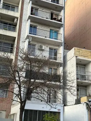 an apartment building with a tree in front of it at Departamento frente a la Ciudad Universitaria in Cordoba