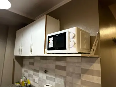 a kitchen with a microwave above a counter at Departamento frente a la Ciudad Universitaria in Cordoba