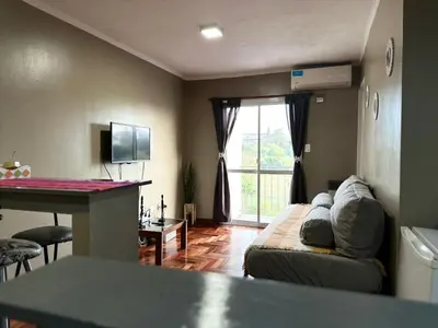 a living room with a couch and a window at Departamento frente a la Ciudad Universitaria in Cordoba
