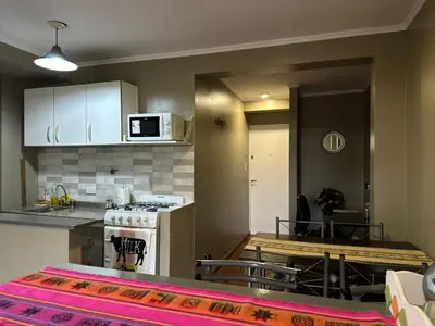 a kitchen and dining room with a table and a stove at Departamento frente a la Ciudad Universitaria in Cordoba