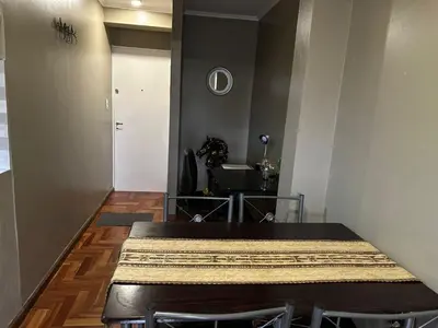 a dining room with a table and a white door at Departamento frente a la Ciudad Universitaria in Cordoba