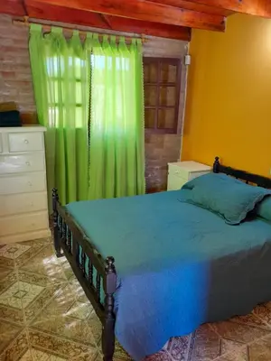 a bedroom with a bed with a green curtain at Cabaña los Lechusos in Cortaderas