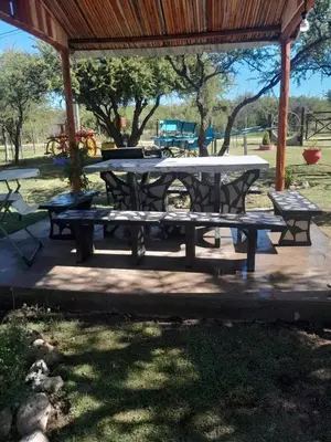 a picnic table and benches under a pavilion at Cabaña los Lechusos in Cortaderas
