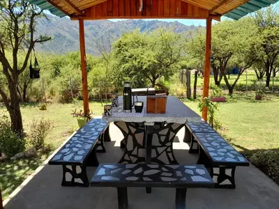 a picnic table with two benches under a gazebo at Cabaña los Lechusos in Cortaderas