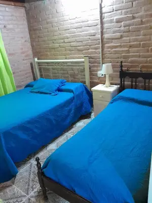 two beds in a room with blue sheets at Cabaña los Lechusos in Cortaderas