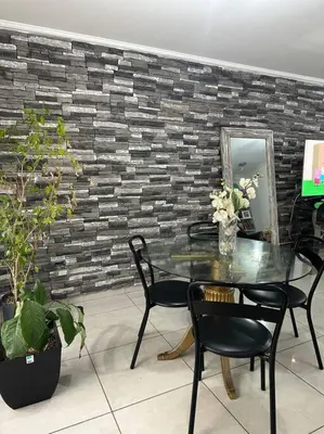 a table and chairs in a room with a brick wall at Departamento espacioso en un complejo residencial, cerca del Shopping nuevo centro in Cordoba