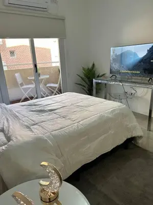 a bedroom with a bed with a table and a television at Departamento espacioso en un complejo residencial, cerca del Shopping nuevo centro in Cordoba