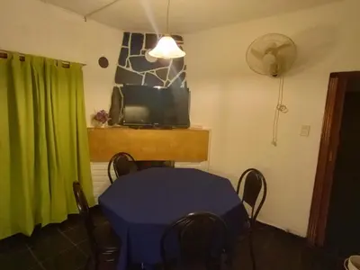 a dining room with a blue table and a television at Casa Tupungato in Villa Carlos Paz