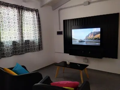a living room with a flat screen tv and two windows at Casa Yowen in Mina Clavero