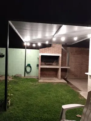 a covered patio with a brick fireplace and lights at Casa Yowen in Mina Clavero