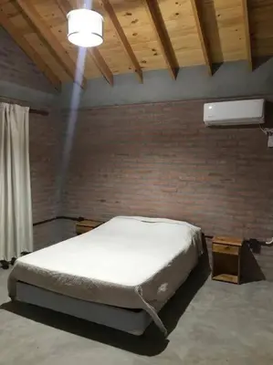 a bedroom with a bed and a brick wall at Cabaña CABEZA DE NIEVE Apta 6 personas in Carpintería