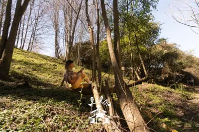 a woman sitting on a tree in the woods at Lila Cumbrecita in La Cumbrecita