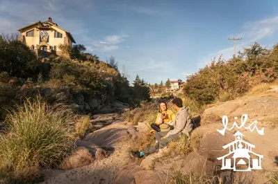 two people sitting on some rocks on a hill at Lila Cumbrecita in La Cumbrecita