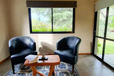 two chairs and a table in a room with windows at Hermosa casa con pileta para dos in Villa General Belgrano
