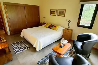 a bedroom with a bed and a table and chairs at Hermosa casa con pileta para dos in Villa General Belgrano