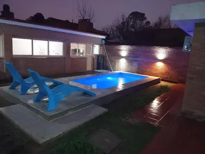 a swimming pool at night with two blue chairs at La casa de Yari in Mina Clavero