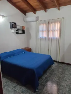 a bedroom with a blue bed and a window at La casa de Yari in Mina Clavero