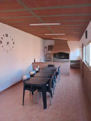a dining room with a long table and a clock on the wall at La casa de Yari in Mina Clavero