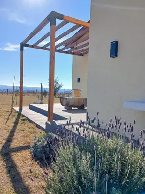 a building with a wooden pergola and purple flowers at La Toscana in Villa Yacanto