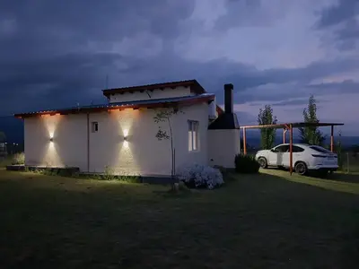a white house with lights on the side of it at La Toscana in Villa Yacanto