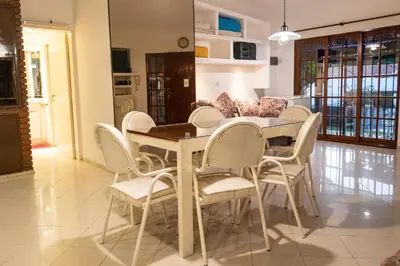 a dining room with a table and white chairs at Casa con pileta exclusiva a 3 cuadras de la costanera Villa Carlos Paz IG alquilervillacarlospaz in Villa Carlos Paz