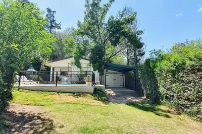 a house with a garage in a yard at Chalet Céntrico con Pileta in Villa General Belgrano