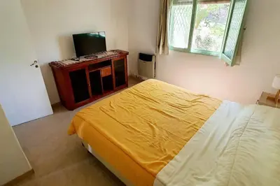 a bedroom with a bed and a television in it at Chalet Céntrico con Pileta in Villa General Belgrano