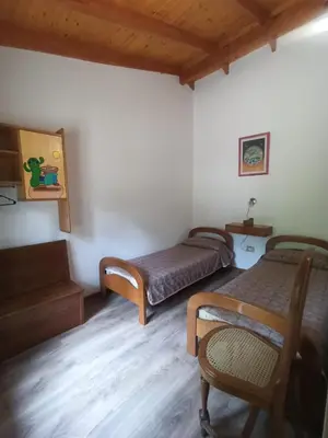 a room with two beds and a chair in it at Casita en Villa General Belgrano in Villa General Belgrano