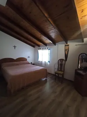 a bedroom with a bed and a cross on the wall at Casita en Villa General Belgrano in Villa General Belgrano