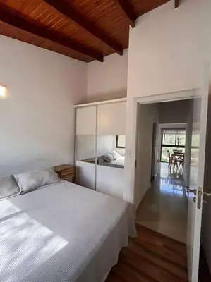 a bedroom with a bed and a room with a table at Departamento con pileta y asadores in Villa General Belgrano