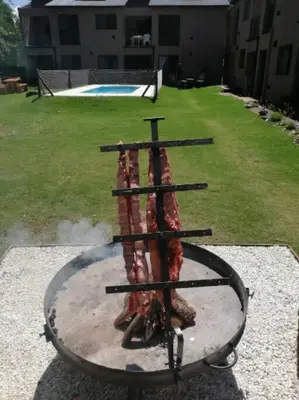 a fire pit with a bunch of meat in it at Departamento con pileta y asadores in Villa General Belgrano
