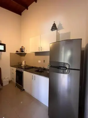 a kitchen with a stainless steel refrigerator and white cabinets at Departamento con pileta y asadores in Villa General Belgrano